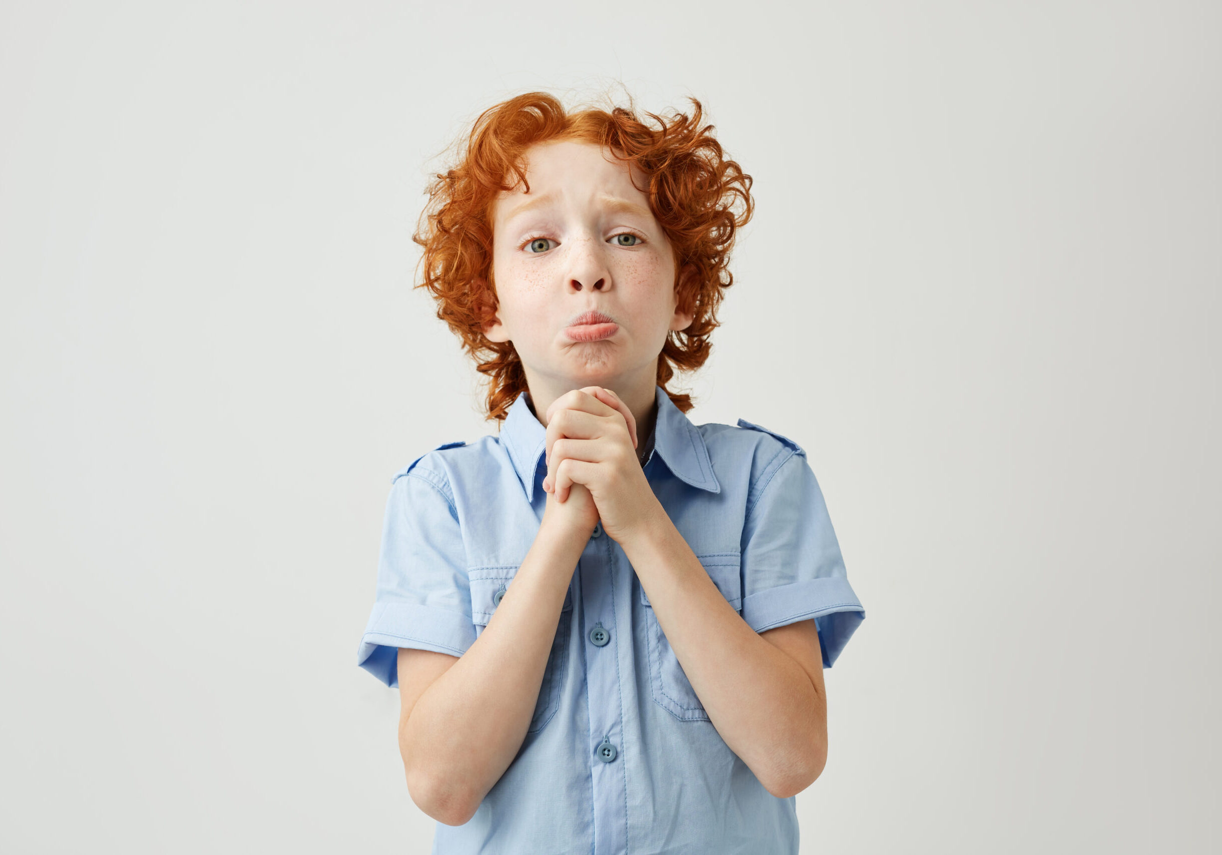 Funny ginger boy with sad and guilty face expression trying apologizes to his mom after lying her about being at school. Body language.